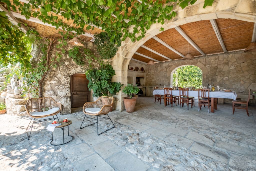Zona pranzo e cena esterna accanto a un antico trullo pugliese sotto un freschissimo pergolato con vite tipica della Puglia